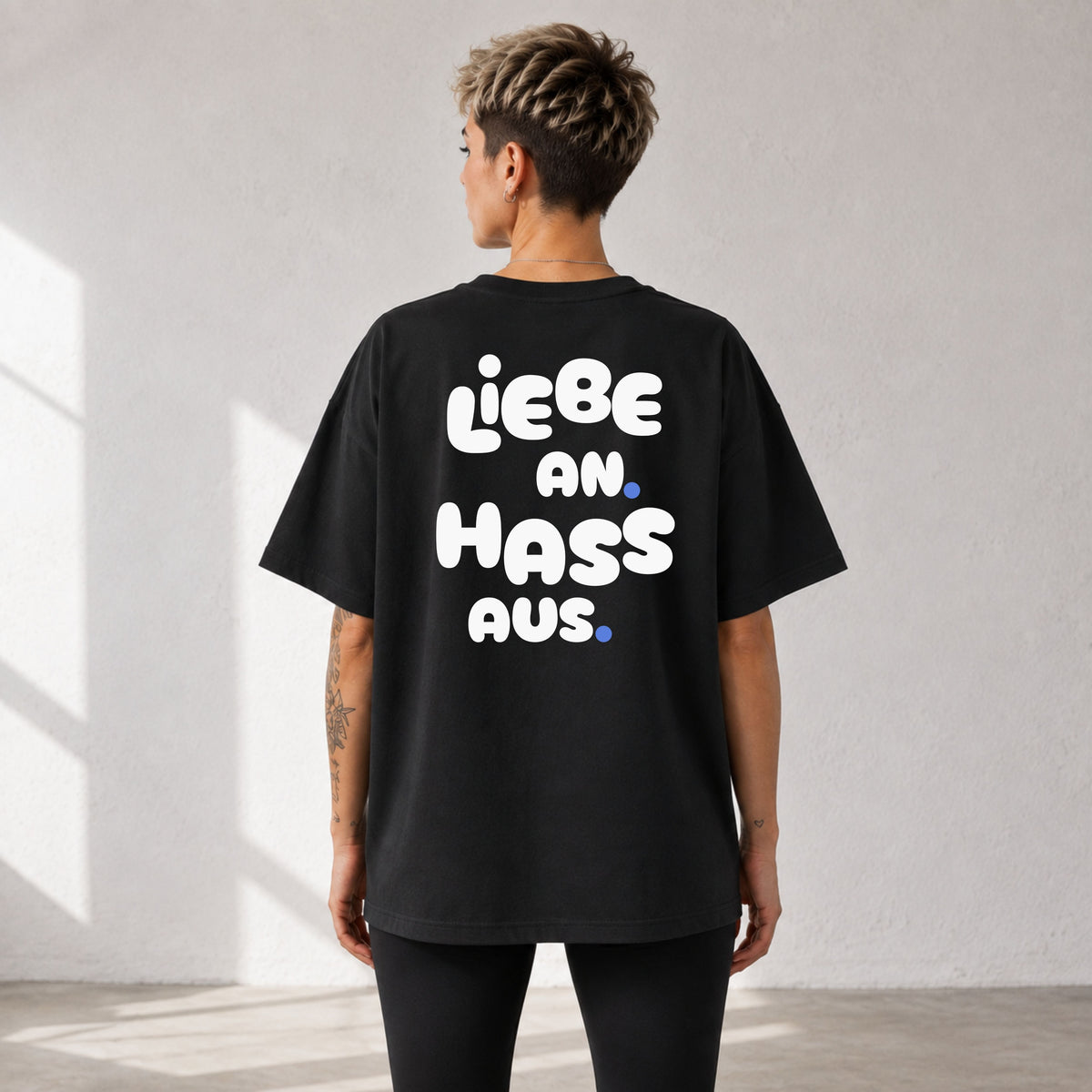     Frau von hinten im schwarzen Oversized Statement Shirt mit „Liebe an. Hass aus.“-Rückenprint