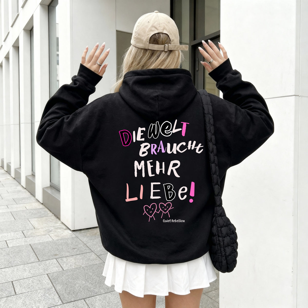 Frau von hinten im schwarzen Statement Hoodie mit „Die Welt braucht mehr Liebe“-Rückenprint